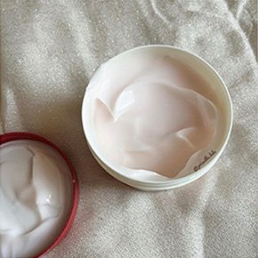 Open tub of creamy product on white blanket