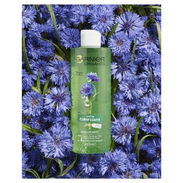 Garnier Organics Cornflower Micellar Water laying in cornflower field